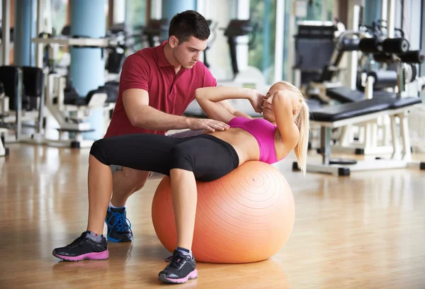 Vrouw met trainer oefenen in fitness gym — Stockfoto
