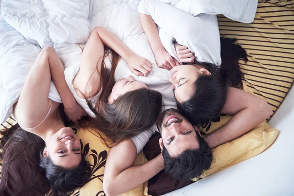 Schöner Mann im Bett mit drei schönen Frauen — Stockfoto