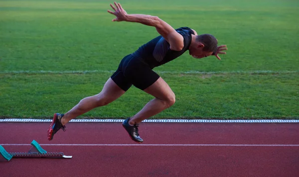 Atletisk mand starter på sporet - Stock-foto