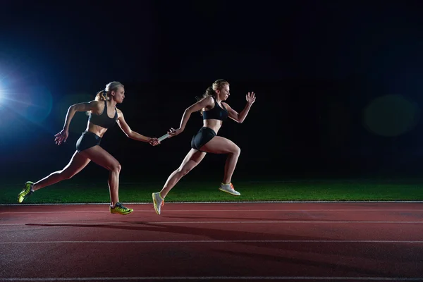 Athletic löpare passerar över stafettpinnen i stafettlopp — Stockfoto
