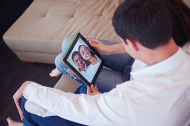 Modern evde tablet bilgisayar kullanan romantik ve rahat genç bir çift.