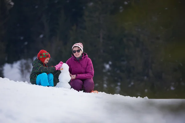 Feliz familia edificio muñeco de nieve — Foto de Stock