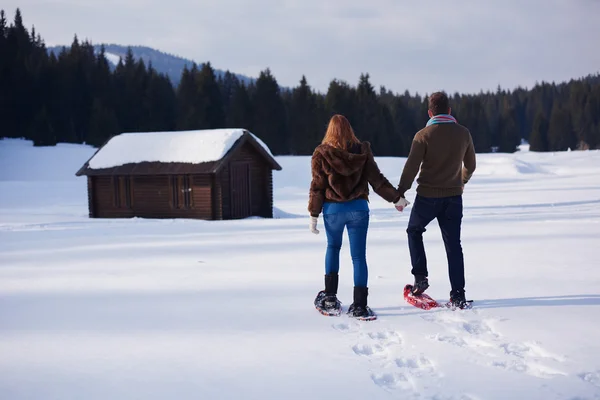 Casal se divertindo e andando em sapatos de neve — Fotografia de Stock