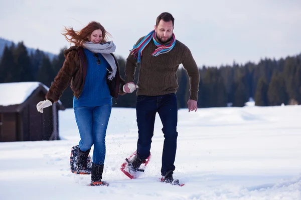 Casal se divertindo e andando em sapatos de neve — Fotografia de Stock