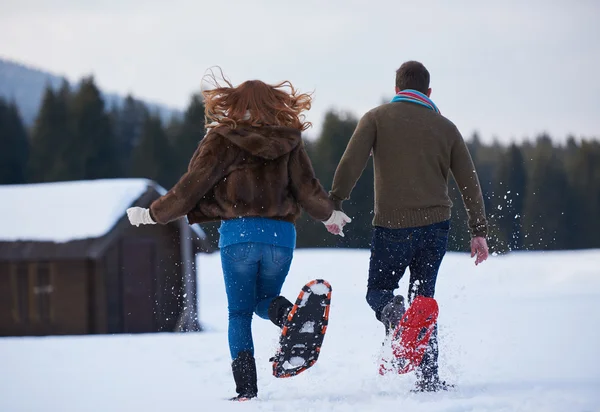 Casal se divertindo e andando em sapatos de neve — Fotografia de Stock