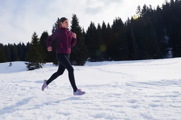 Молода жінка біжить на відкритому повітрі на снігу в лісі — стокове фото