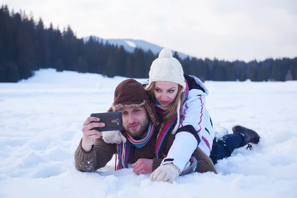 romantic couple having fun in fresh snow and taking selfie