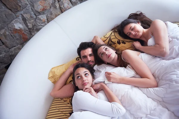 ผู้ชายหล่อบนเตียงกับผู้หญิงสวยสามคน — ภาพถ่ายสต็อก