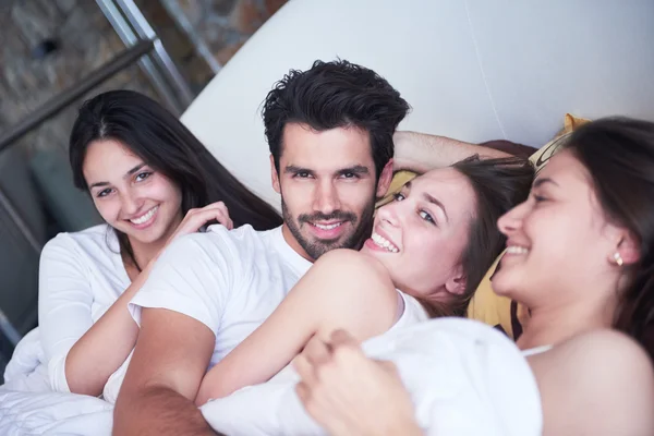 Schöner Mann im Bett mit drei schönen Frauen — Stockfoto