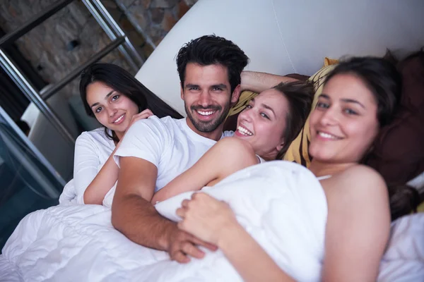 Hombre guapo en la cama con tres hermosas mujeres — Foto de Stock