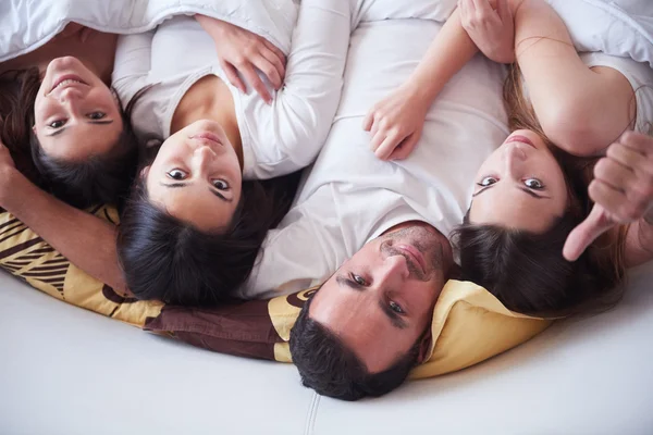 Hombre guapo en la cama con tres hermosas mujeres —  Fotos de Stock