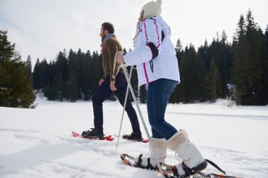 couple having fun and walking in snow shoes clipart
