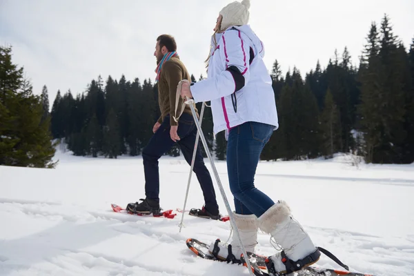 Pareja divirtiéndose y caminando en zapatos de nieve — Foto de Stock