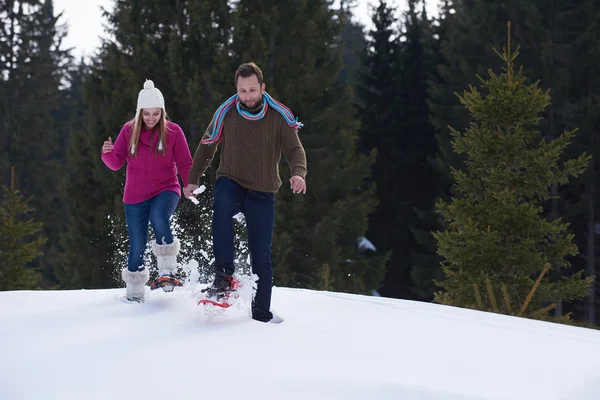 Casal se divertindo e andando em sapatos de neve — Fotografia de Stock