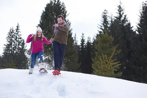 Pareja divirtiéndose y caminando en zapatos de nieve —  Fotos de Stock