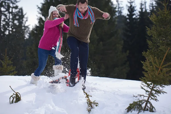 Casal se divertindo e andando em sapatos de neve — Fotografia de Stock