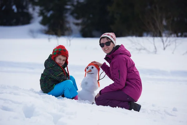 Gelukkig familie gebouw sneeuwpop — Stockfoto