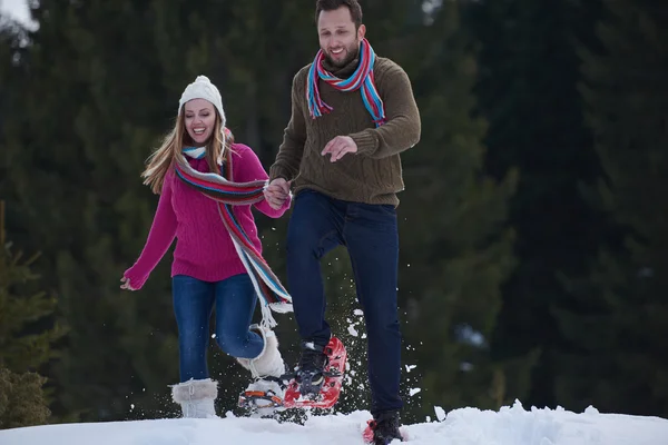 Casal se divertindo e andando em sapatos de neve — Fotografia de Stock