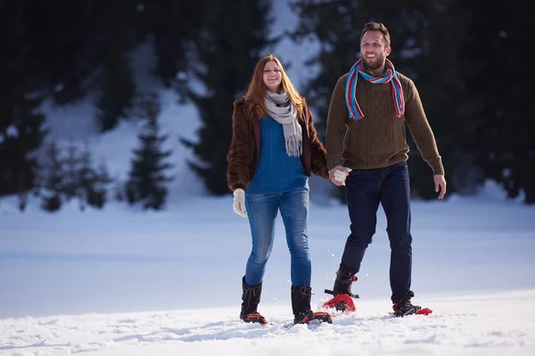 Casal se divertindo e andando em sapatos de neve — Fotografia de Stock