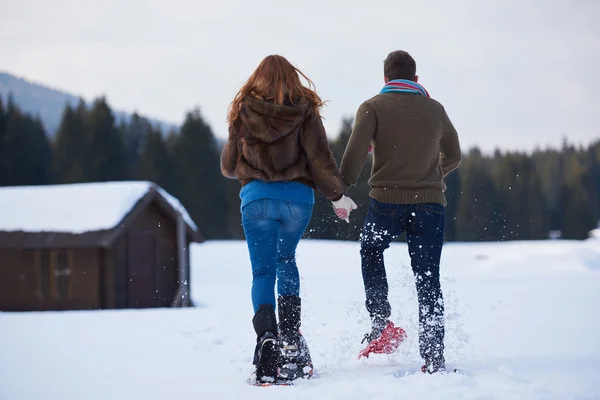 Casal se divertindo e andando em sapatos de neve — Fotografia de Stock