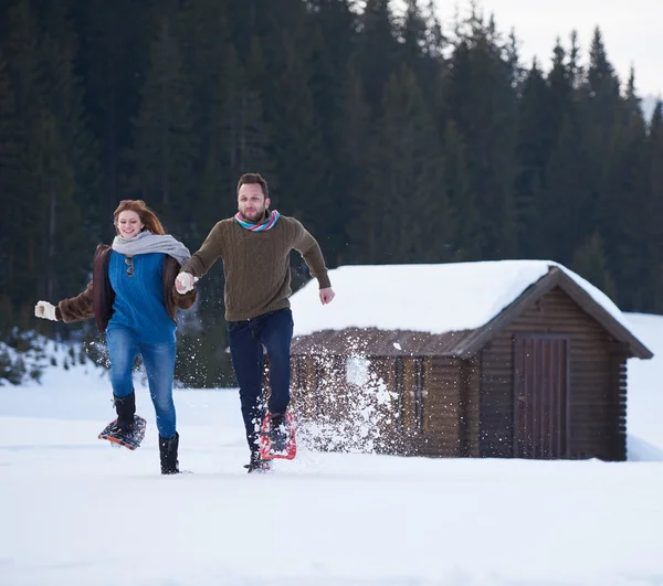 Pareja divirtiéndose y caminando en zapatos de nieve — Foto de Stock