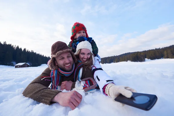 Family having fun in fresh snow and taking selfie — Stok fotoğraf