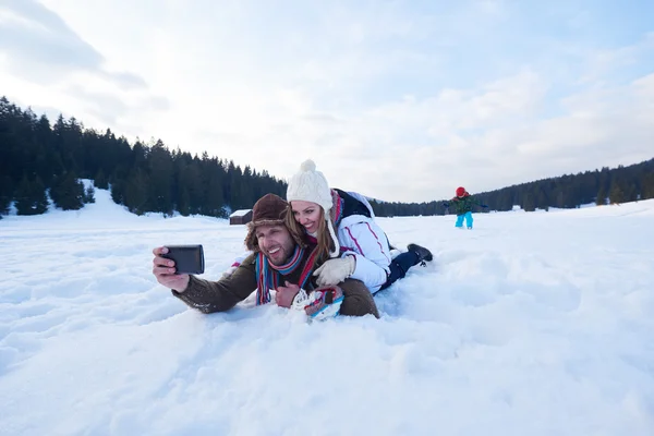 Pareja romántica divertirse en la nieve fresca y tomar selfie —  Fotos de Stock