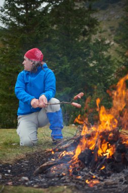 Hiking adam kamp ateşi üzerinde lezzetli sosis hazırlamak