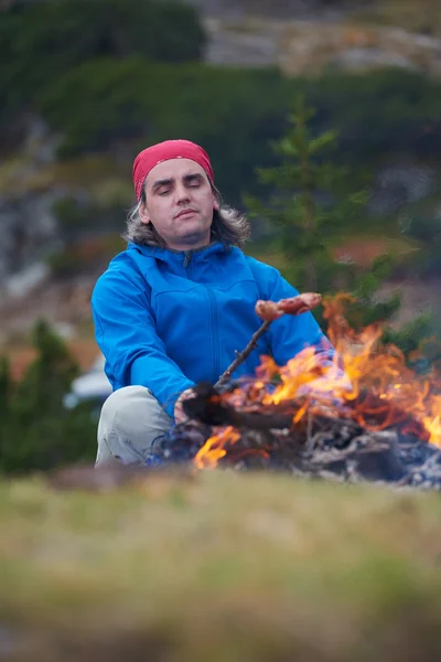 Hiking man prepare tasty sausages on campfire — Stock Photo, Image