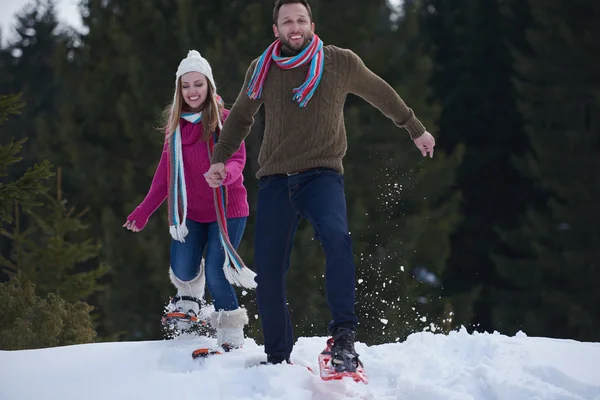 Casal se divertindo e andando em sapatos de neve — Fotografia de Stock