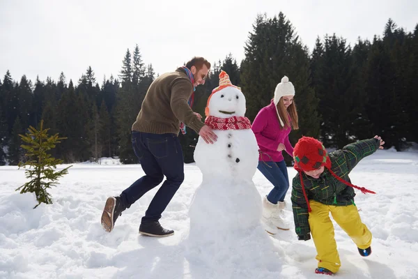 Glückliche Familie baut Schneemann — Stockfoto