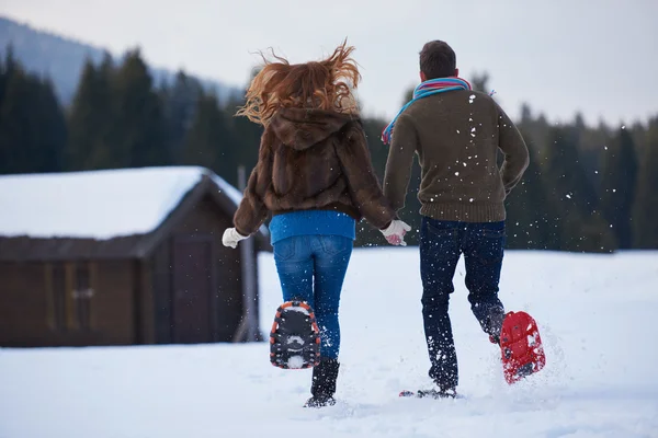 Casal se divertindo e andando em sapatos de neve — Fotografia de Stock