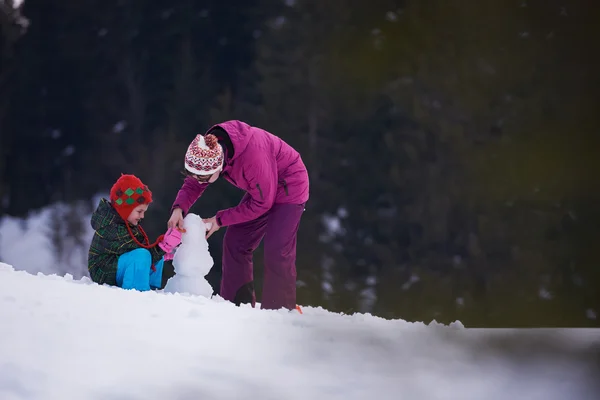Matka a syn, budování sněhulák — Stock fotografie
