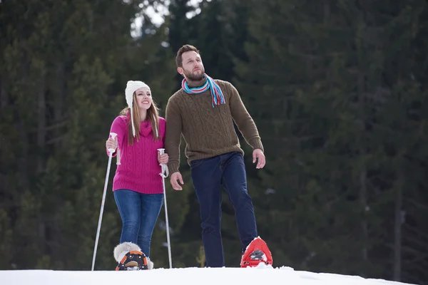 Pareja divirtiéndose y caminando en zapatos de nieve — Foto de Stock