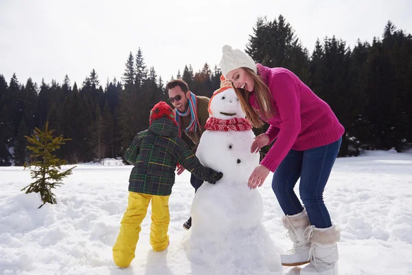 Glückliche Familie baut Schneemann — Stockfoto