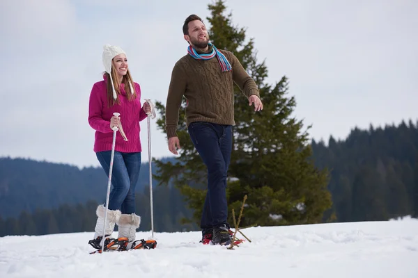 Casal se divertindo e andando em sapatos de neve — Fotografia de Stock