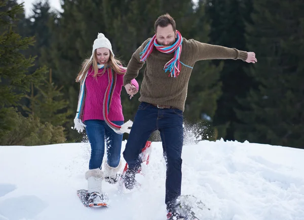 Eğleniyor ve kar ayakkabı yürürken bir çift — Stok fotoğraf