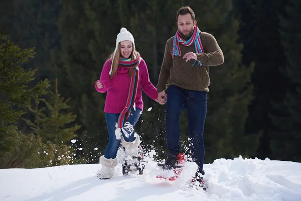 Casal se divertindo e andando em sapatos de neve — Fotografia de Stock