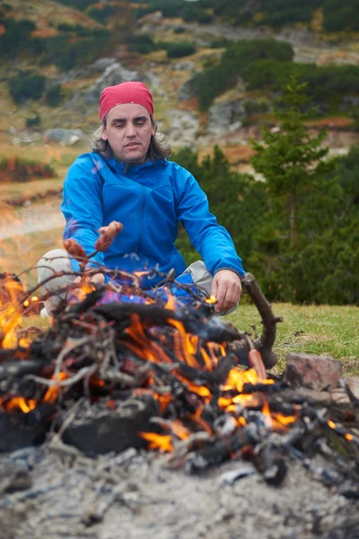 Hiking adam kamp ateşi üzerinde lezzetli sosis hazırlamak — Stok fotoğraf
