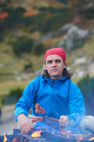L'escursionista prepara gustose salsicce sul falò — Foto Stock