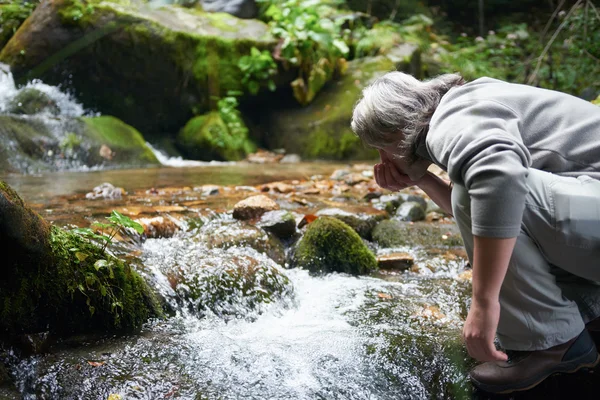 Uomo che beve acqua dolce dalla primavera — Foto Stock