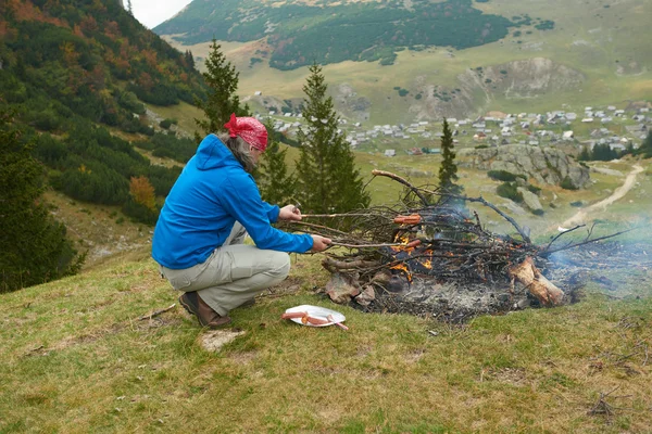 徒步旅行的人准备美味的香肠，在篝火上 — 图库照片