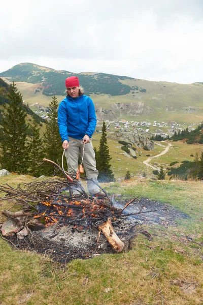 Randonnée homme préparer de savoureuses saucisses sur le feu de camp — Photo