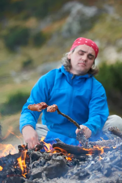 Homem caminhadas preparar saborosas salsichas na fogueira — Fotografia de Stock