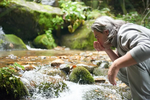 Homem bebendo água doce da primavera — Fotografia de Stock