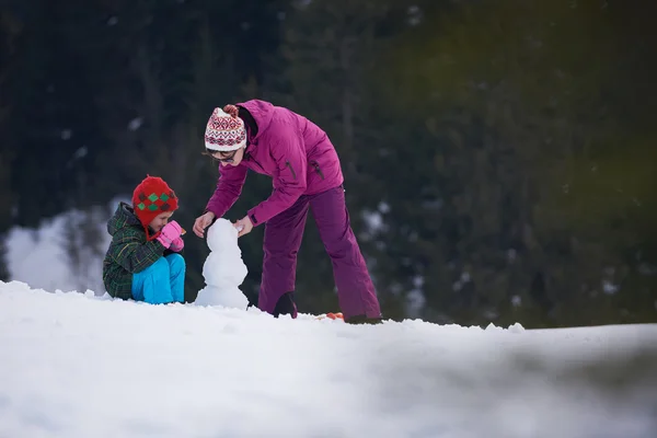 Mère et fils construction bonhomme de neige — Photo