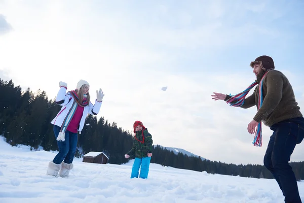 Счастливая семья, играющая вместе в снегу зимой — стоковое фото