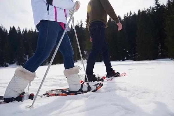 Pareja divirtiéndose y caminando en zapatos de nieve — Foto de Stock