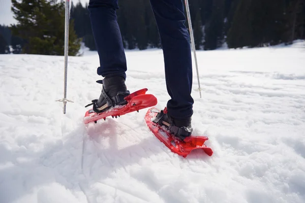 Homem andando em sapatos de neve — Fotografia de Stock