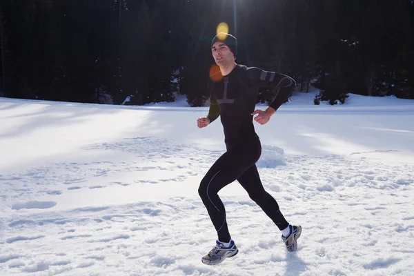 Man jogging on snow in forest — Stock Photo, Image